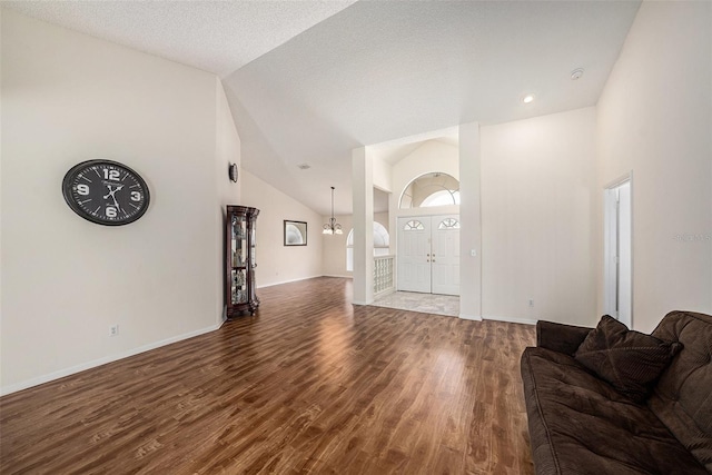 14181 Cornewall Ln, Spring Hill, FL 34609 - living room featuring wood finished floors, high vaulted ceiling, french doors, baseboards, and a chandelier