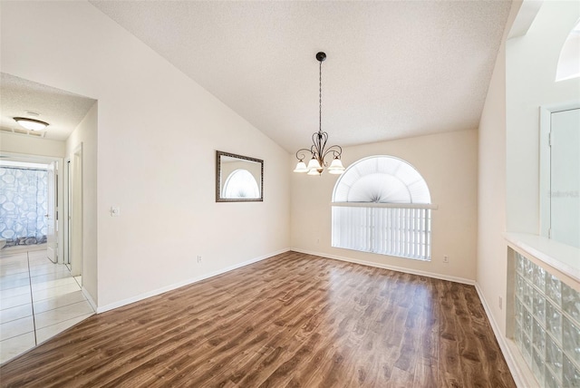 14181 Cornewall Ln, Spring Hill, FL 34609 - empty room with wood finished floors, a textured ceiling, a chandelier, vaulted ceiling, and baseboards