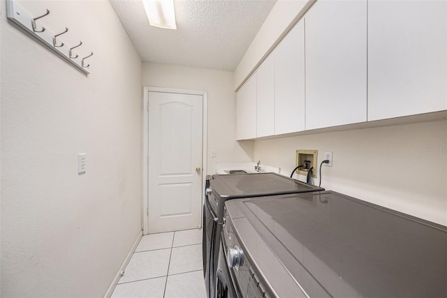 14181 Cornewall Ln, Spring Hill, FL 34609 - laundry room featuring cabinet space, a textured ceiling, washing machine and dryer, light tile patterned floors, and baseboards
