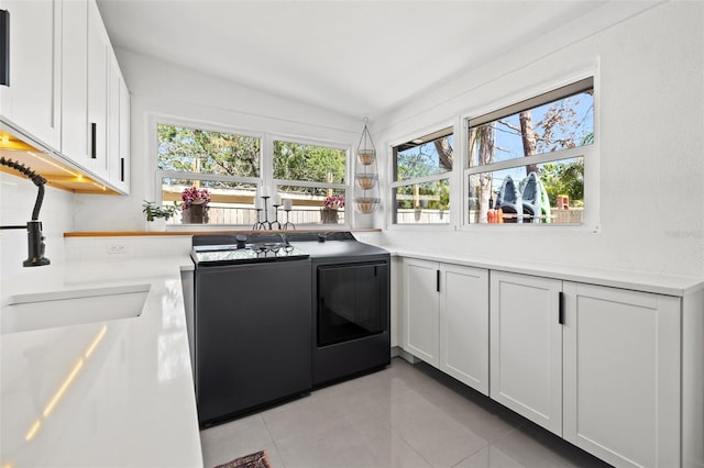 310 55th Ave S, Saint Petersburg, FL 33705 - kitchen featuring separate washer and dryer, light tile patterned floors, a sink, dishwasher, and white cabinets
