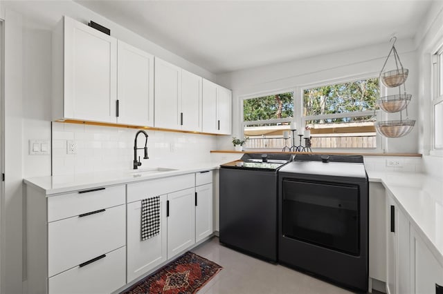310 55th Ave S, Saint Petersburg, FL 33705 - kitchen with separate washer and dryer, a sink, backsplash, white cabinetry, and light countertops