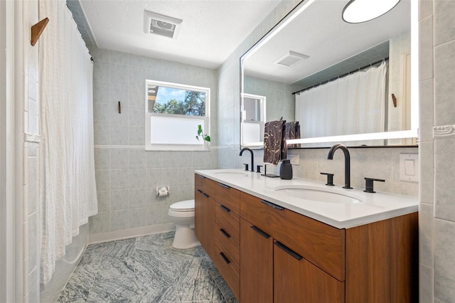 310 55th Ave S, Saint Petersburg, FL 33705 - full bath with tile walls, double vanity, toilet, and a shower with shower curtain