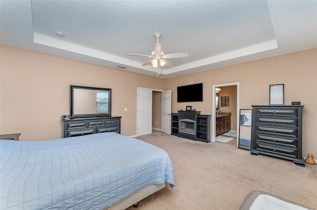 11206 Coventry Grove Cir, Lithia, FL 33547 - bedroom with a tray ceiling, light carpet, ceiling fan, and a fireplace