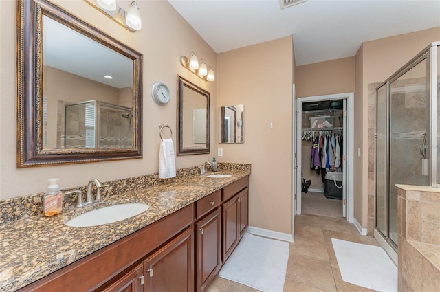 11206 Coventry Grove Cir, Lithia, FL 33547 - bathroom with a shower stall, double vanity, a walk in closet, tile patterned floors, and baseboards