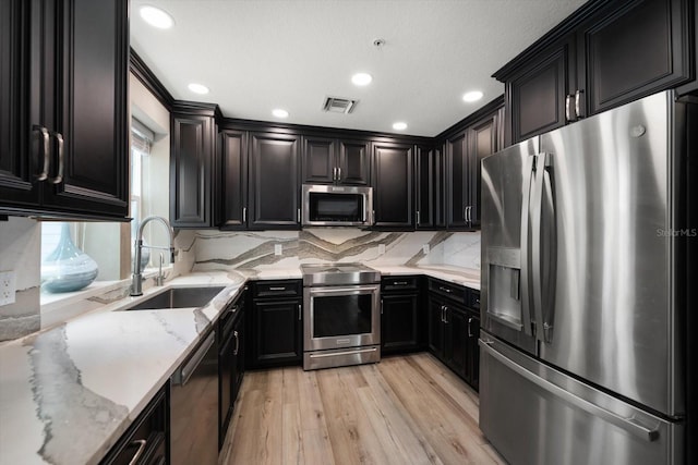 215 18th Ave, Indian Rocks Beach, FL 33785 - kitchen featuring stainless steel appliances, a sink, light wood-style floors, light stone countertops, and tasteful backsplash