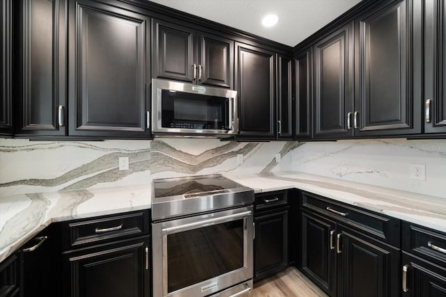 215 18th Ave, Indian Rocks Beach, FL 33785 - kitchen featuring appliances with stainless steel finishes, dark cabinets, light stone counters, and decorative backsplash