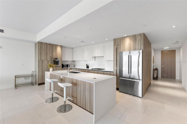 1020 Sunset Point Rd Unit 410, Clearwater, FL 33756 - kitchen featuring appliances with stainless steel finishes, modern cabinets, light countertops, a center island with sink, and a breakfast bar area