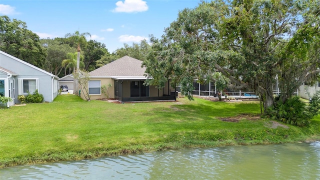 9721 Fredericksburg Rd, Tampa, FL 33635 - back of house with a sunroom, a lawn, stucco siding, and a water view