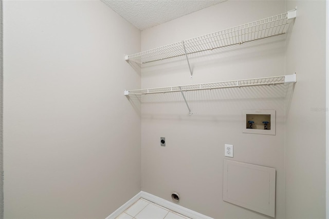 9721 Fredericksburg Rd, Tampa, FL 33635 - laundry room with electric dryer hookup, washer hookup, baseboards, tile patterned flooring, and a textured ceiling