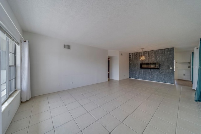 2441 Persian Dr Unit 61, Clearwater, FL 33763 - unfurnished living room with healthy amount of natural light, a textured ceiling, light tile patterned flooring, and a large fireplace