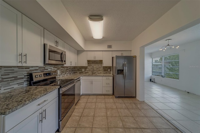 2441 Persian Dr Unit 61, Clearwater, FL 33763 - kitchen featuring appliances with stainless steel finishes, decorative backsplash, white cabinets, light stone countertops, and a textured ceiling