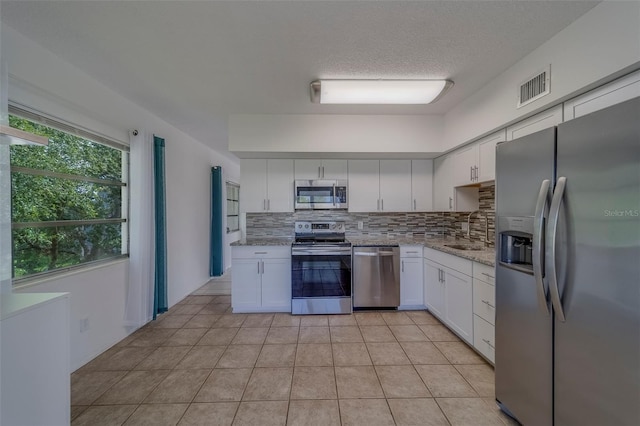 2441 Persian Dr Unit 61, Clearwater, FL 33763 - kitchen featuring stainless steel appliances, a sink, decorative backsplash, white cabinetry, and light stone countertops