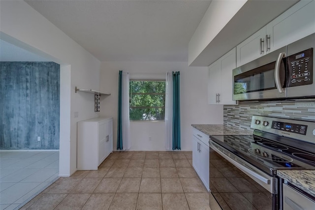 2441 Persian Dr Unit 61, Clearwater, FL 33763 - kitchen with appliances with stainless steel finishes, tasteful backsplash, white cabinets, light tile patterned flooring, and light stone counters