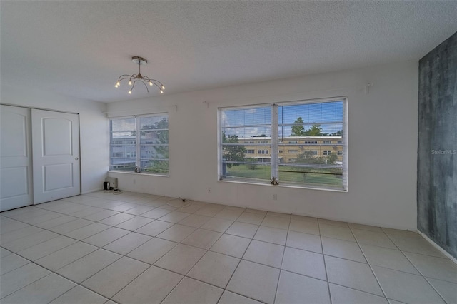 2441 Persian Dr Unit 61, Clearwater, FL 33763 - unfurnished dining area featuring a chandelier, a textured ceiling, plenty of natural light, and light tile patterned flooring