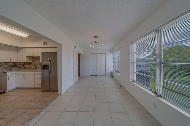 2441 Persian Dr Unit 61, Clearwater, FL 33763 - kitchen featuring stainless steel fridge, a chandelier, light tile patterned floors, decorative backsplash, and light stone counters