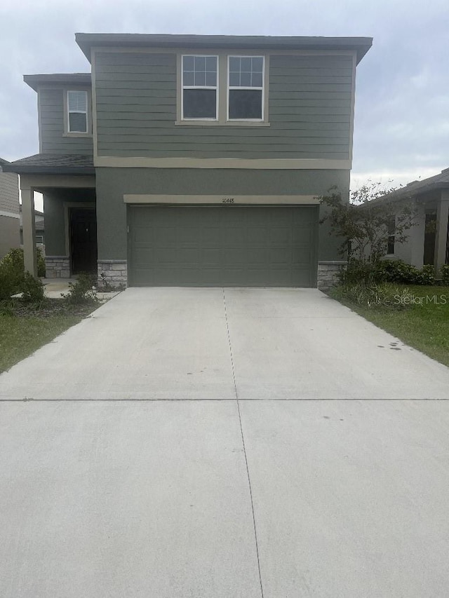 10448 Ladybug Cv, Parrish, FL 34219 - view of front of house featuring an attached garage, stone siding, concrete driveway, and stucco siding