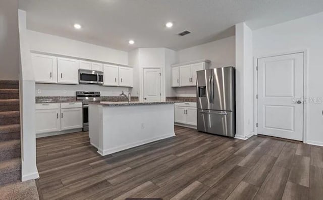10448 Ladybug Cv, Parrish, FL 34219 - kitchen featuring appliances with stainless steel finishes, white cabinets, dark wood-style floors, recessed lighting, and a center island with sink