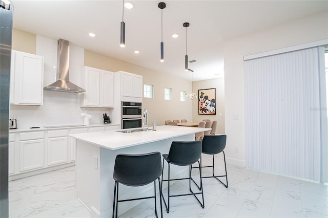 1430 Reunion Blvd, Reunion, FL 34747 - kitchen with wall chimney range hood, light marble finish floors, black electric stovetop, recessed lighting, and a breakfast bar area