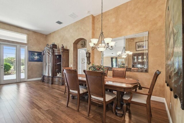3402 Stonebridge Trl, Valrico, FL 33596 - dining space featuring arched walkways, baseboards, a chandelier, wood finished floors, and a towering ceiling