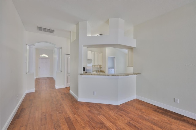 11726 S Stone Ln, Riverview, FL 33569 - kitchen with arched walkways, ornate columns, wood finished floors, light stone countertops, and baseboards