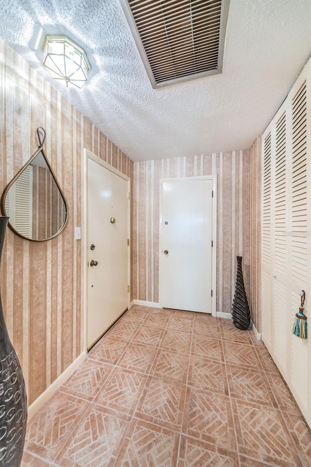 100 Bluff View Dr Unit 514C, Belleair Bluffs, FL 33770 - entryway featuring a textured ceiling, baseboards, and wallpapered walls