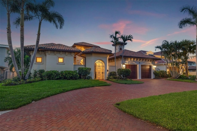 301 Bayview Dr NE, Saint Petersburg, FL 33704 - mediterranean / spanish-style home featuring curved driveway, stucco siding, a garage, a front lawn, and a tiled roof