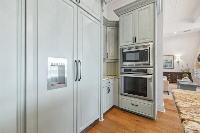 301 Bayview Dr NE, Saint Petersburg, FL 33704 - kitchen with built in appliances, light wood-type flooring, light stone countertops, and gray cabinets