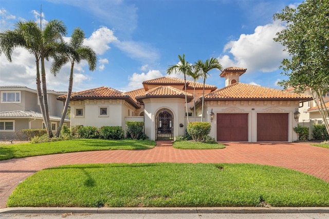301 Bayview Dr NE, Saint Petersburg, FL 33704 - mediterranean / spanish home featuring an attached garage, a tiled roof, stucco siding, and a front lawn
