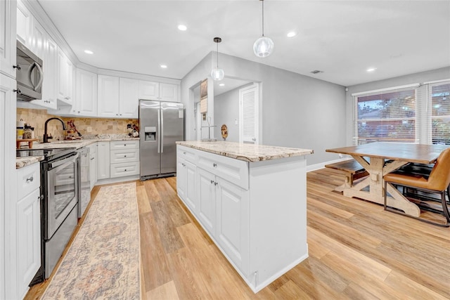 4726 W Fairview Hts, Tampa, FL 33616 - kitchen with stainless steel appliances, a sink, a kitchen island, light wood finished floors, and white cabinets
