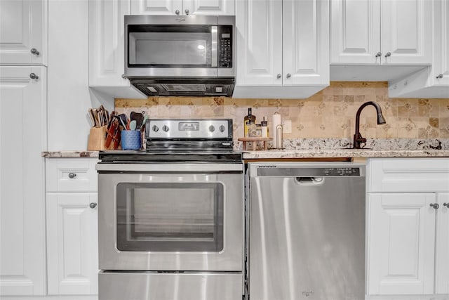 4726 W Fairview Hts, Tampa, FL 33616 - kitchen featuring stainless steel appliances, white cabinets, decorative backsplash, light stone countertops, and exhaust hood