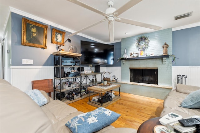 708 Westwood Cir, Brandon, FL 33511 - living room featuring a wainscoted wall, ceiling fan, ornamental molding, wood finished floors, and a brick fireplace