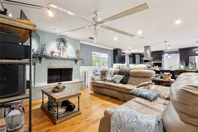 708 Westwood Cir, Brandon, FL 33511 - living area with ceiling fan, light wood-style flooring, a brick fireplace, crown molding, and a wainscoted wall