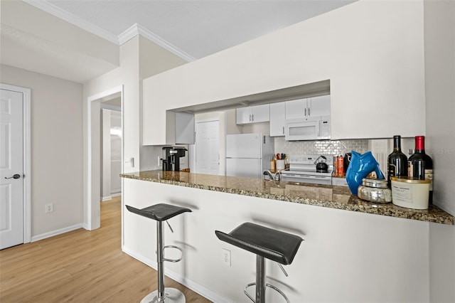 800 S Dakota Ave Unit 337, Tampa, FL 33606 - kitchen featuring white appliances, a peninsula, light wood finished floors, crown molding, and tasteful backsplash