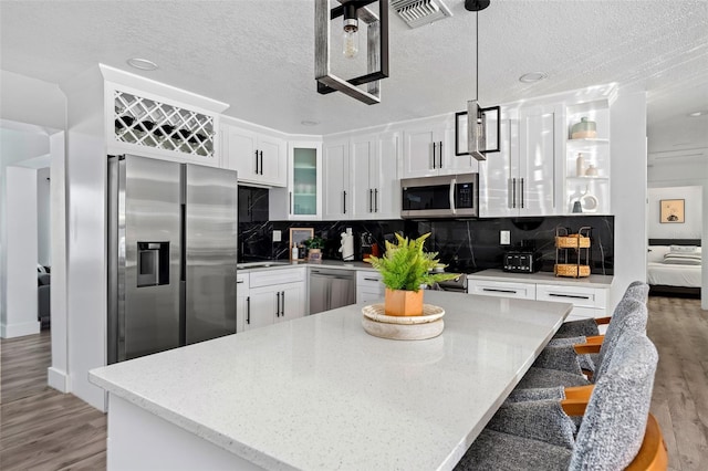3485 Floral Dr, Largo, FL 33771 - kitchen featuring appliances with stainless steel finishes, light wood-style floors, white cabinetry, a textured ceiling, and backsplash