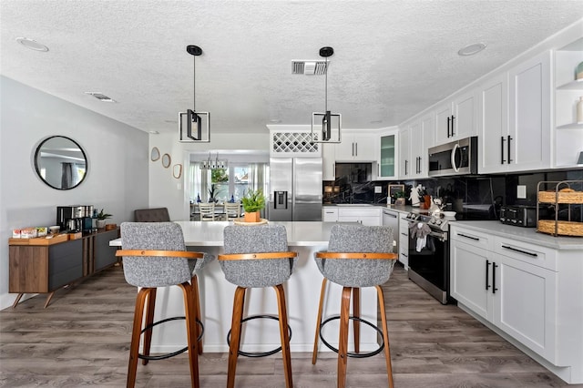 3485 Floral Dr, Largo, FL 33771 - kitchen featuring stainless steel appliances, open shelves, a center island, white cabinetry, and a kitchen bar