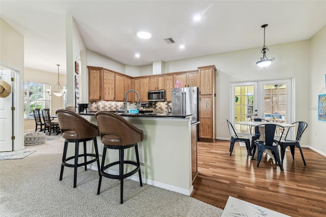 10306 Shalimar Wood Dr, Thonotosassa, FL 33592 - kitchen with appliances with stainless steel finishes, dark countertops, a kitchen bar, decorative backsplash, and pendant lighting
