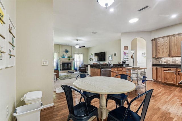 10306 Shalimar Wood Dr, Thonotosassa, FL 33592 - dining space featuring ceiling fan, arched walkways, light wood-style flooring, a glass covered fireplace, and recessed lighting