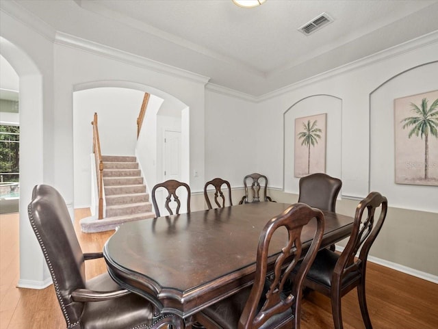 6127 Cezanne Ave, Lutz, FL 33558 - dining room featuring arched walkways, wood finished floors, stairs, crown molding, and baseboards