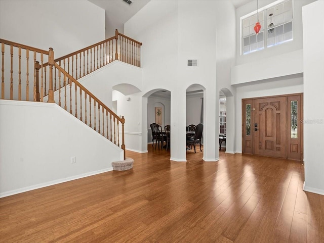 6127 Cezanne Ave, Lutz, FL 33558 - foyer entrance featuring arched walkways, wood finished floors, stairs, a towering ceiling, and baseboards
