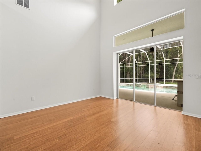 6127 Cezanne Ave, Lutz, FL 33558 - empty room with wood finished floors, baseboards, and a high ceiling