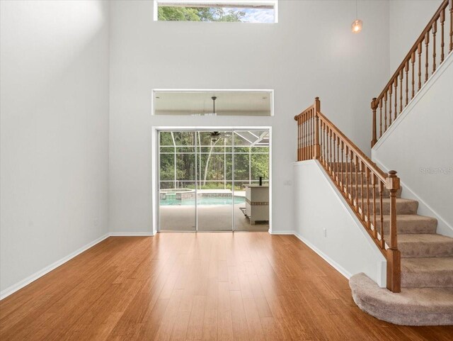 6127 Cezanne Ave, Lutz, FL 33558 - unfurnished living room featuring a high ceiling, wood finished floors, stairs, baseboards, and a sunroom