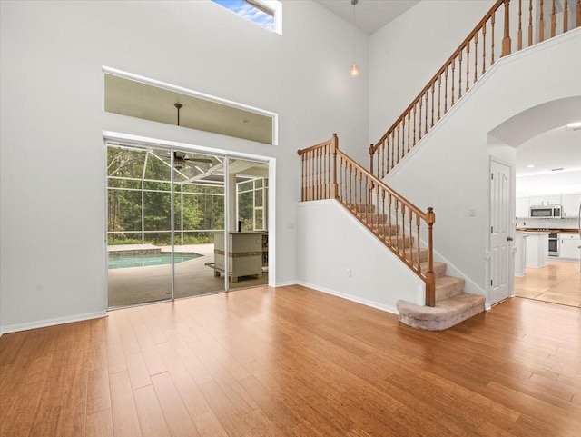 6127 Cezanne Ave, Lutz, FL 33558 - unfurnished living room featuring a high ceiling, wood finished floors, arched walkways, ceiling fan, and plenty of natural light