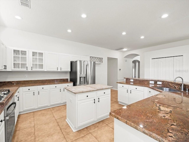 6127 Cezanne Ave, Lutz, FL 33558 - kitchen with stainless steel appliances, arched walkways, a sink, a kitchen island, and glass insert cabinets