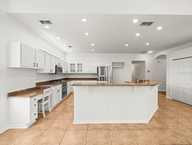 6127 Cezanne Ave, Lutz, FL 33558 - kitchen featuring stainless steel appliances, a kitchen bar, white cabinets, arched walkways, and light tile patterned flooring