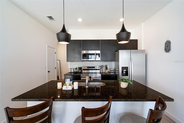 3428 Tranquil Trl, Kissimmee, FL 34747 - kitchen with stainless steel appliances, a kitchen bar, dark cabinetry, backsplash, and a sink