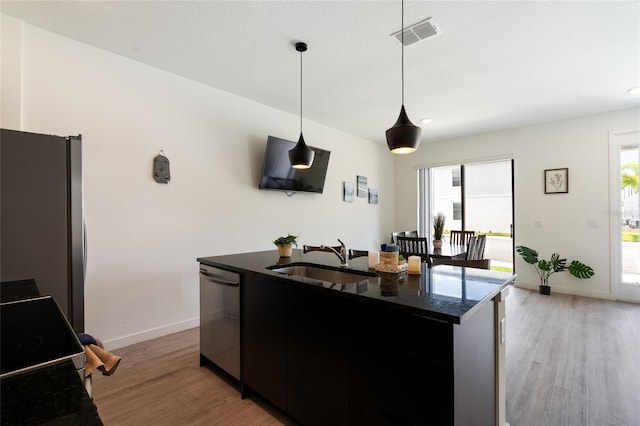 3428 Tranquil Trl, Kissimmee, FL 34747 - kitchen with stainless steel appliances, a sink, light wood-style floors, and dark cabinetry