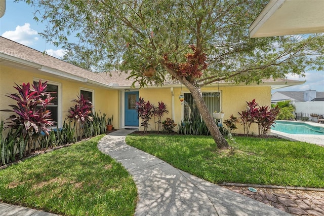 15005 Roundup Dr, Tampa, FL 33624 - view of front facade featuring stucco siding, a front lawn, and a shingled roof