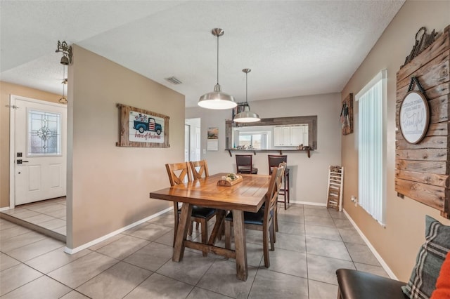 15005 Roundup Dr, Tampa, FL 33624 - dining space featuring a textured ceiling, plenty of natural light, light tile patterned flooring, and baseboards
