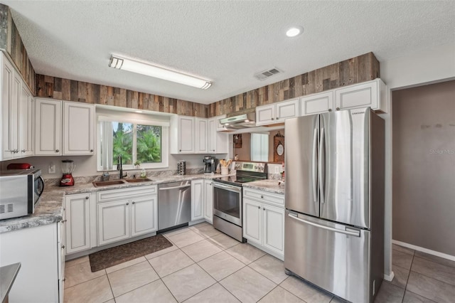 15005 Roundup Dr, Tampa, FL 33624 - kitchen featuring stainless steel appliances, a sink, a textured ceiling, white cabinetry, and light tile patterned floors