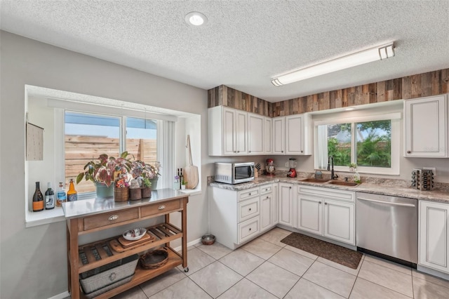 15005 Roundup Dr, Tampa, FL 33624 - kitchen featuring stainless steel appliances, a sink, healthy amount of natural light, a textured ceiling, and white cabinets